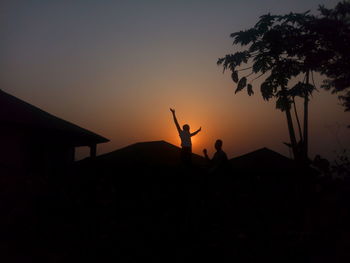 Silhouette people by tree against sky during sunset