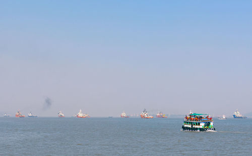 Boats sailing in sea against clear sky