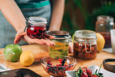 Woman holding jars with fermented fruits.