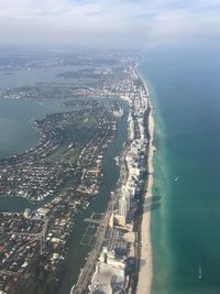 Aerial view of city by sea against sky