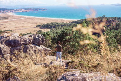 Rear view of man standing by sea against sky