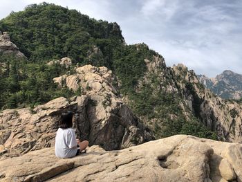 Rear view of woman sitting on rock