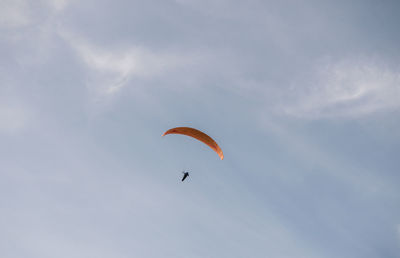 Low angle view of person paragliding against sky