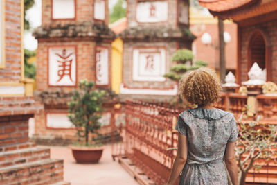 Rear view of woman walking against building