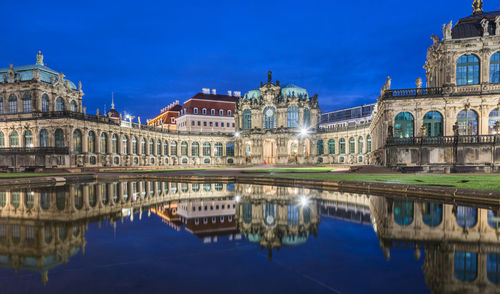 Zwinger museum reflecting on lake against blue sky