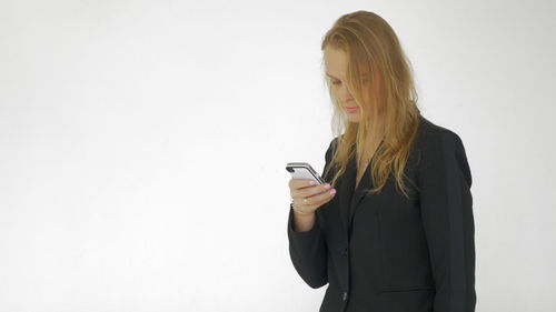 Young woman looking away while standing against white background