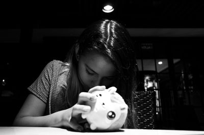 Girl holding toy on table in darkroom at home