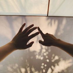 Cropped image of people hands gesturing by shadow on curtain