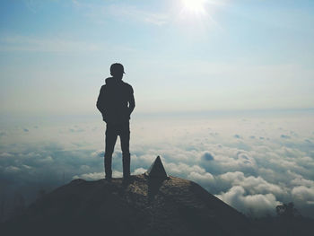 Silhouette man standing on rock against sky during sunset