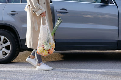 Young woman putting reusable shopping bag with groceries into the car. sustainable lifestyle