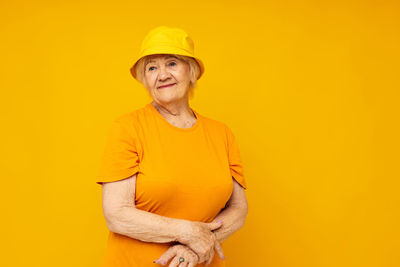 Portrait of young man standing against yellow background