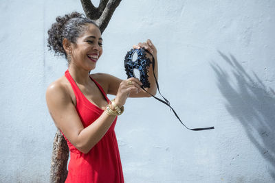 Portrait of a woman holding a carnival mask against a light blue wall. salvador, bahia, brazil.