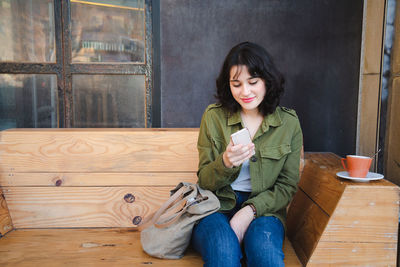 Full length of young woman using mobile phone