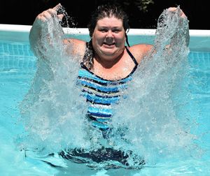 Portrait of smiling woman splashing water in swimming pool