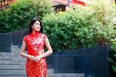 Portrait of young woman standing against plants