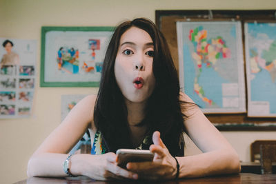 Portrait of young surprised woman using mobile phone