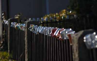 Close-up of mugs hanging on metal fence