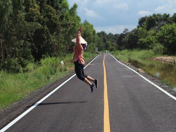 Rear view of man jumping on road