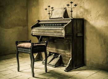 Chair by piano against wall in old room