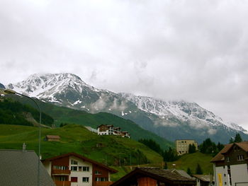 Houses by snowcapped mountain against sky