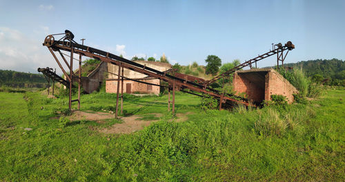 Rusty metallic structure on field against sky