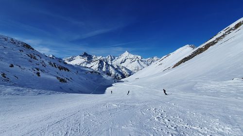 Scenic view of snowcapped mountains against blue sky