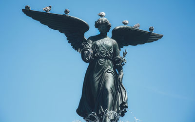 Low angle view of angel statue against clear blue sky