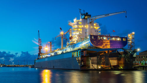 Illuminated commercial dock against blue sky at night