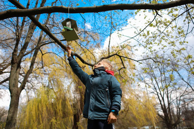 Rear view of man standing by bare trees