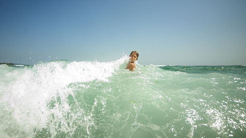 Man swimming in sea against clear sky