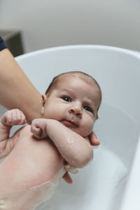 Cropped hands of mother bathing baby girl in bathtub