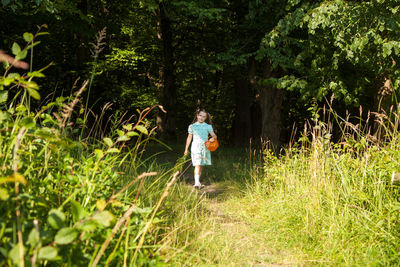 Full length of girl walking on grassy field in forest