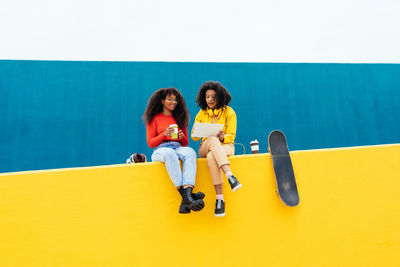 Smiling friends sitting on wall