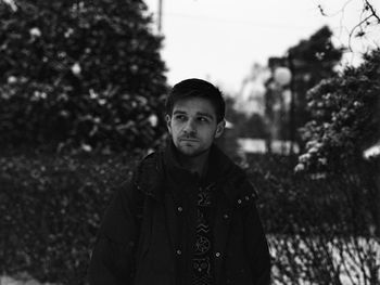 Thoughtful man looking away while standing against sky during winter