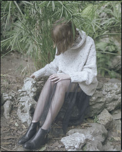 Rear view of woman sitting on rock