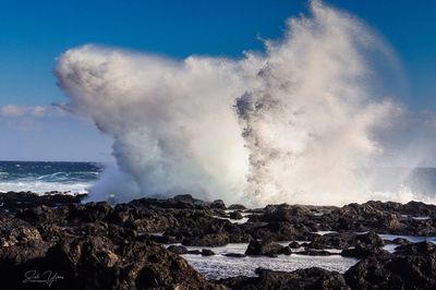 Panoramic view of sea waves against rocks