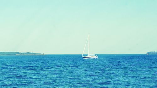 Sailboat sailing in sea against clear sky