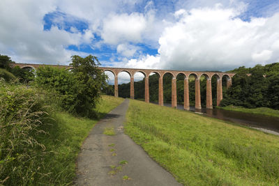 Road by arch bridge against sky