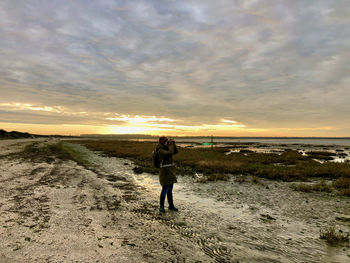 Rear view of friends standing on beach during sunset