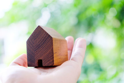 Cropped hand of person holding model home outdoors