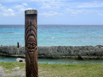 Carved pole against tropical sea