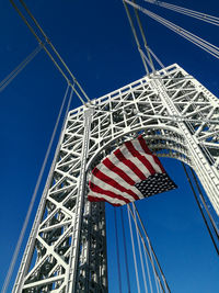 Low angle view of american flag at george washington bridge against clear blue sky