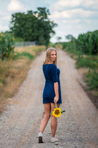 Full length of woman standing on footpath by road