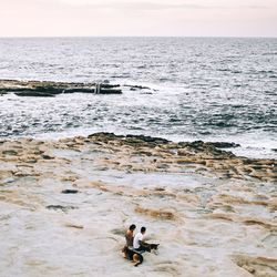 Friends at sea shore against sky