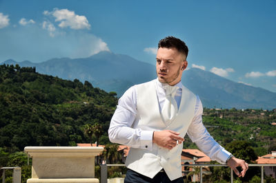 Businessman smoking cigarette by railing against mountains