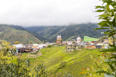 Houses by trees and mountains against sky