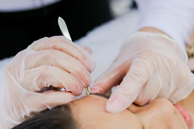 Cropped hand of beautician using tool on female customer