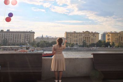 Woman standing by buildings against sky in city