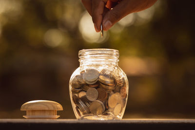 Close-up of hand holding glass jar on table