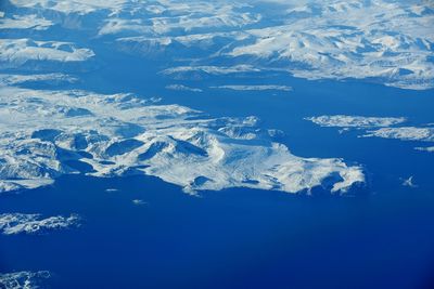 Aerial view of snowcapped mountains against blue sky